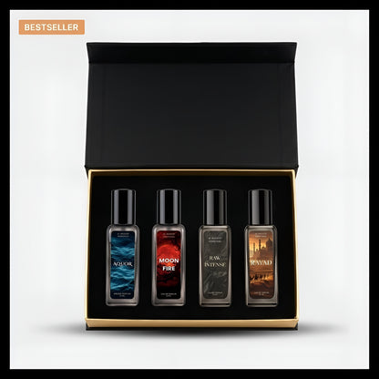 A boxed set of four fragrance oil bottles presented in an open black gift box with a gold inner trim, on a light gray background. The bottles have black caps and dark glass, with labels in blue, red, gray, and brown tones.
